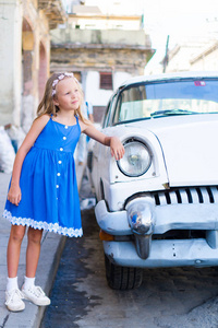 可爱的小女孩在老哈瓦那，古巴的流行地区。孩子背景经典美国老爷车的肖像