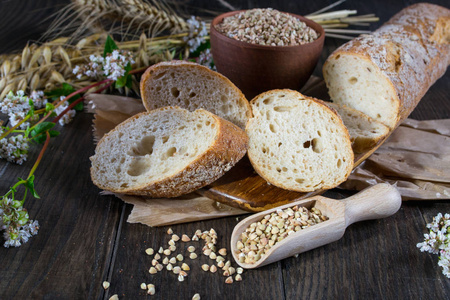 面包店的概念。荞麦面包 法国面包和秸秆的小麦 燕麦 荞麦黑木制的桌子上