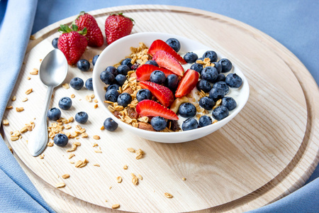 健康早餐的概念。格兰诺拉麦片，蓝莓和草莓，白碗