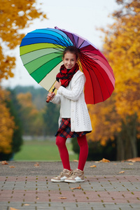 在秋天公园彩虹伞下的女孩