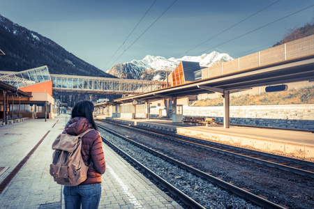 坐在高山铁路火车旅行。在平台上，在背景雪山女孩等待火车