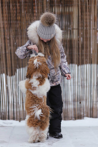 女孩在冬天雪天在森林里玩她的小狗