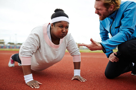 专项体育教练鼓励超重的年轻女子在练习俯卧撑时更努力