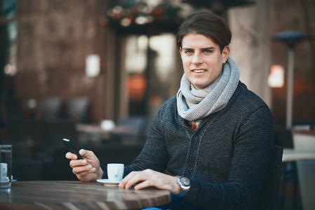 坐在咖啡馆的人使用智能手机和喝咖啡