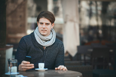 坐在咖啡馆的人使用智能手机和喝咖啡