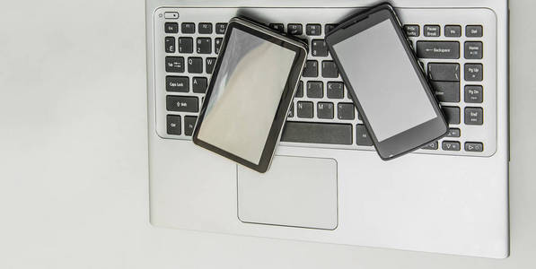 一套现代化的电脑设备。隔离在白色。智能手机和 gps 导航空屏幕放在笔记本电脑键盘上。空白的地方写白色背景信息