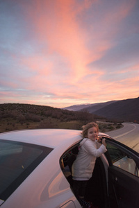 快乐的小女孩开车去度假。山路上的日落