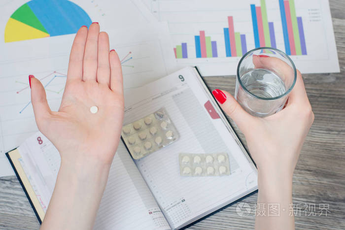 一只手拿着药片的女人和另一个在水上的玻璃