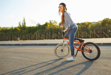 可爱的年轻女子，在一顶帽子，在城市的背景下骑自行车