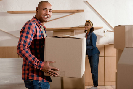 快乐的非洲裔美国人夫妇拿着纸板箱搬到新公寓