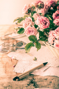 戴着眼镜木制的桌子上的粉红玫瑰
