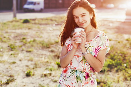 漂亮小女孩微笑着走在街与早晨喝咖啡
