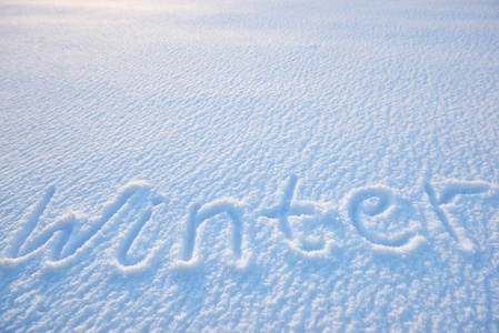 冬天文字在雪为纹理或背景冬天假日概念写。阳光明媚的日子, 明亮的灯光与阴影, 平躺, 顶部视图, 干净, 没有人