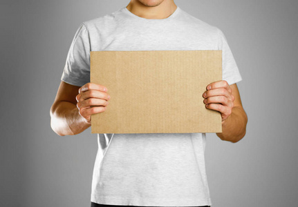 一个穿着白色 t恤的年轻人拿着一块纸板前