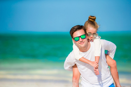 快乐的父亲和孩子一起在白色的热带海滩上