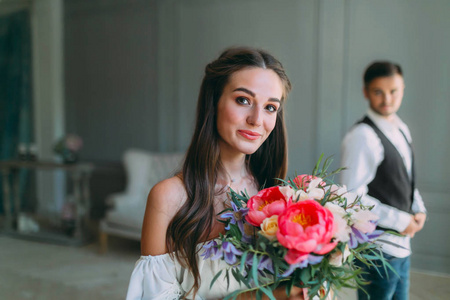 性格开朗，年轻新娘与新郎模糊背景的婚礼花束的特写肖像。一个快乐的女孩，摆了一束花