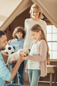 美丽的年轻家庭与拉布拉多小狗在纸板房子前面