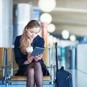 国际机场的年轻女子在等待她的航班时读一本书