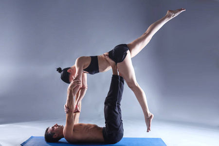 年轻夫妇一起练习杂技瑜伽工作室在垫子上。杂技。几个瑜伽。双人瑜伽