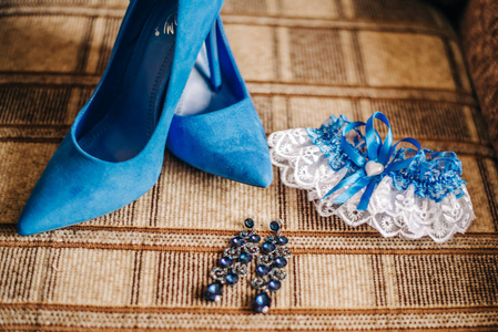 带耳环的蓝色高跟鞋和新娘腿的吊袜带