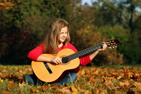 美丽的女孩与吉他在公园