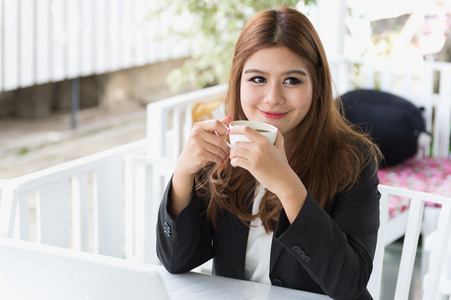 亚洲年轻的商界女人坐在咖啡馆里喝热咖啡