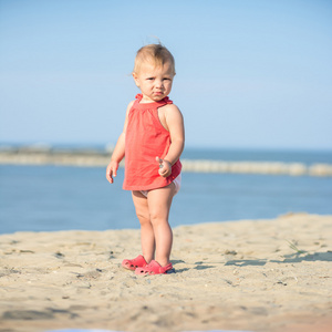 宝贝女孩穿着红色在海边的沙滩上玩