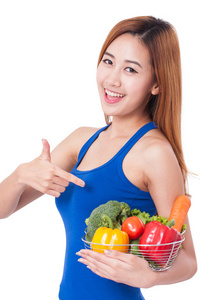 快乐的年轻女子捧着篮子的蔬菜。健康概念