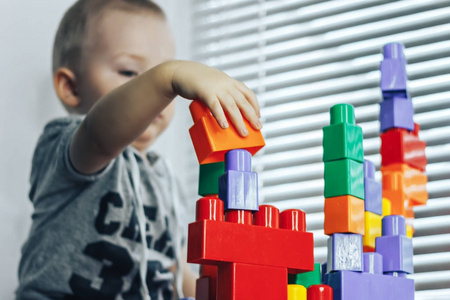 宝宝玩 constructorlittle 婴儿玩的许多丰富多彩的塑料积木附近的窗口构造函数