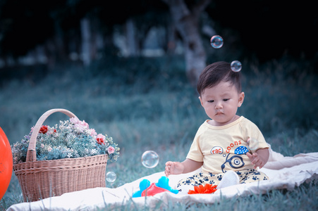 亚洲宝贝小男孩坐在绿草与肥皂泡沫
