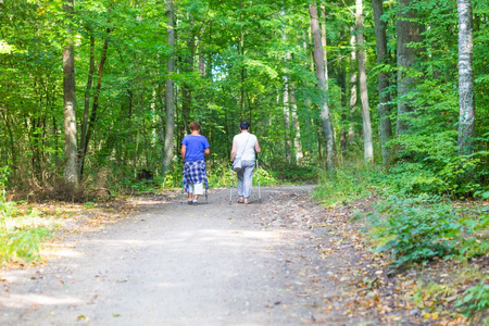 两个老女人北欧步行穿过森林路径