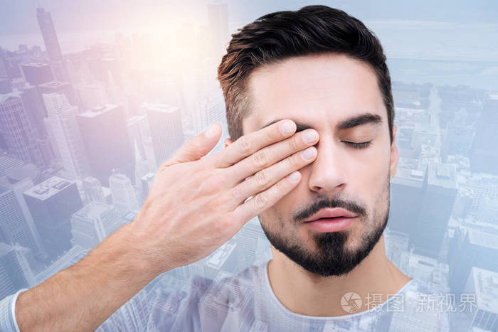 疲惫的年轻男子触摸他的眼睛