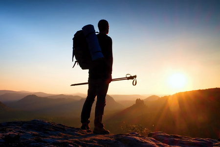 锋利的高个子山顶与太阳在框架中的剪影。山区旅游指南