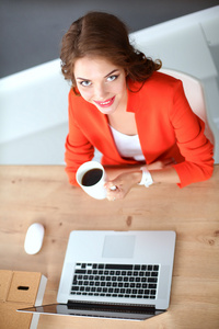有吸引力的女人坐在桌前在办公室使用便携式计算机