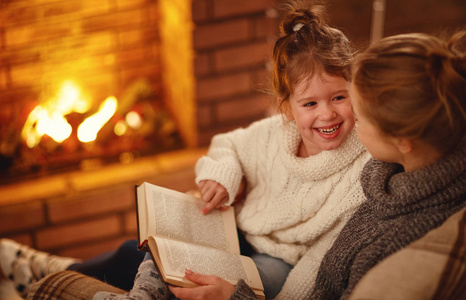 愉快的家庭母亲和孩子女儿读书在冬天 eveni