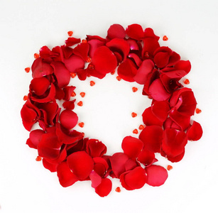 红玫瑰的花瓣和红色的心在白色的背景花圈。顶部视图。复制空间。假日概念