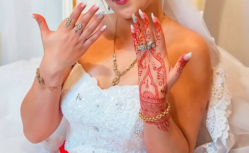 新娘持有男子戒指。新娘把钉子钉在她的手上。新娘手里拿着一个棕色的戒指。新娘显示她的指甲花, 戒指和脸颊