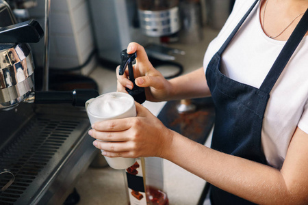 特写镜头年轻的白种女人的女性咖啡手加入甜调味糖浆在杯杯 cappucino 咖啡。人在工作, 小企业概念