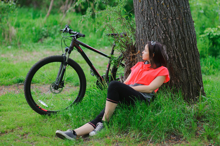 在一棵树附近骑自行车后休息的女孩