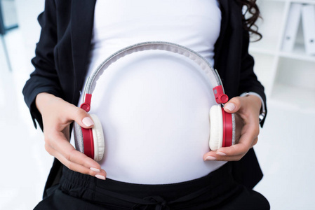 怀孕女商人戴着耳机在肚子上图片