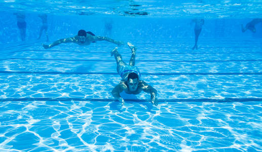 水下乐趣。两个年轻英俊的男人在水下游泳, 在游泳池里跳水。体育和休闲