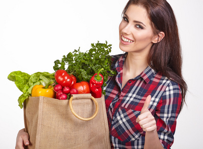 孤立的女人抱着一个装满了蔬菜的购物袋