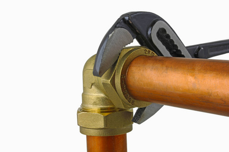 水管工的可调扳手拧紧铜管道可调扳手拧紧在白色背景下的15mm 铜管道的压缩弯头配件