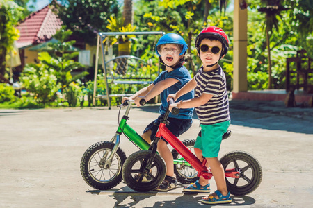 两个小男孩在一个国家的热带公路上的平衡自行车乐趣