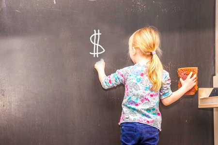 可爱的小女孩在黑板上写美元符号