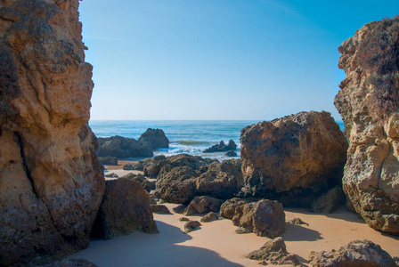 野生的夏天的海滩，葡萄牙。晴朗的天空，在沙子上的岩石
