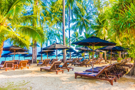 伞和坐在椅子上热带海滩图片