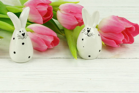 复活节兔子和一束粉红色的郁金香在白色的木制背景。复制空间