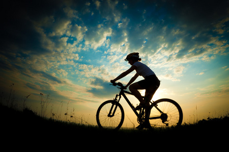 骑自行车的女孩在草地上日落