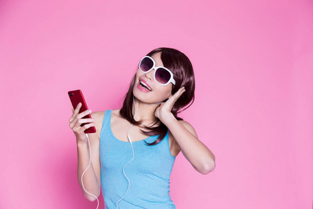 妇女使用电话和听音乐在粉红色背景